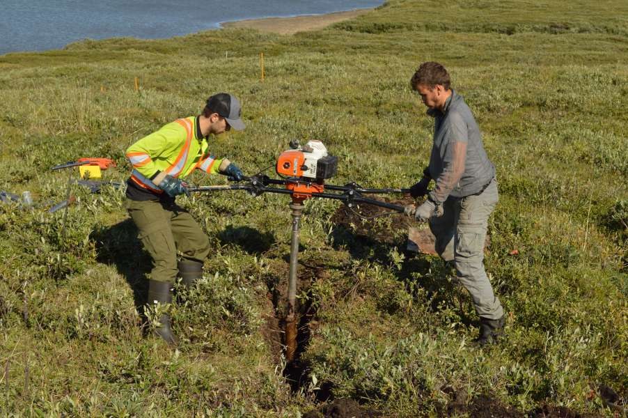 Drilling into ice wedge T2 at Illisarvik, August 2022, with field assistant Aidan Gill. A gas auger and a 50 mm core barrel, working across the trench hole by hole.